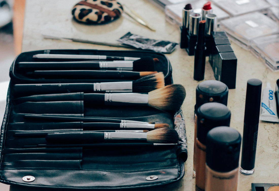 Beautifully organized makeup collection with brushes and products neatly arranged. Makeup brushes in a black case on a table with makeup products.