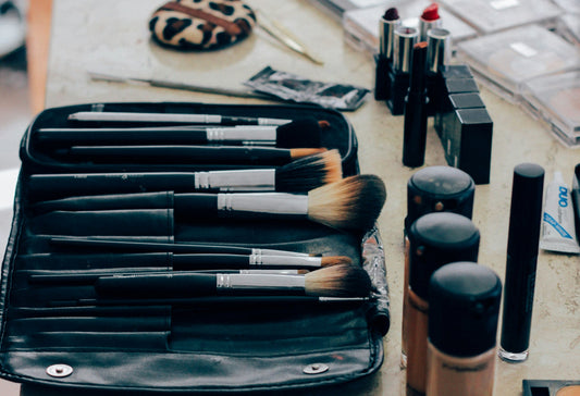 Beautifully organized makeup collection with brushes and products neatly arranged. Makeup brushes in a black case on a table with makeup products.