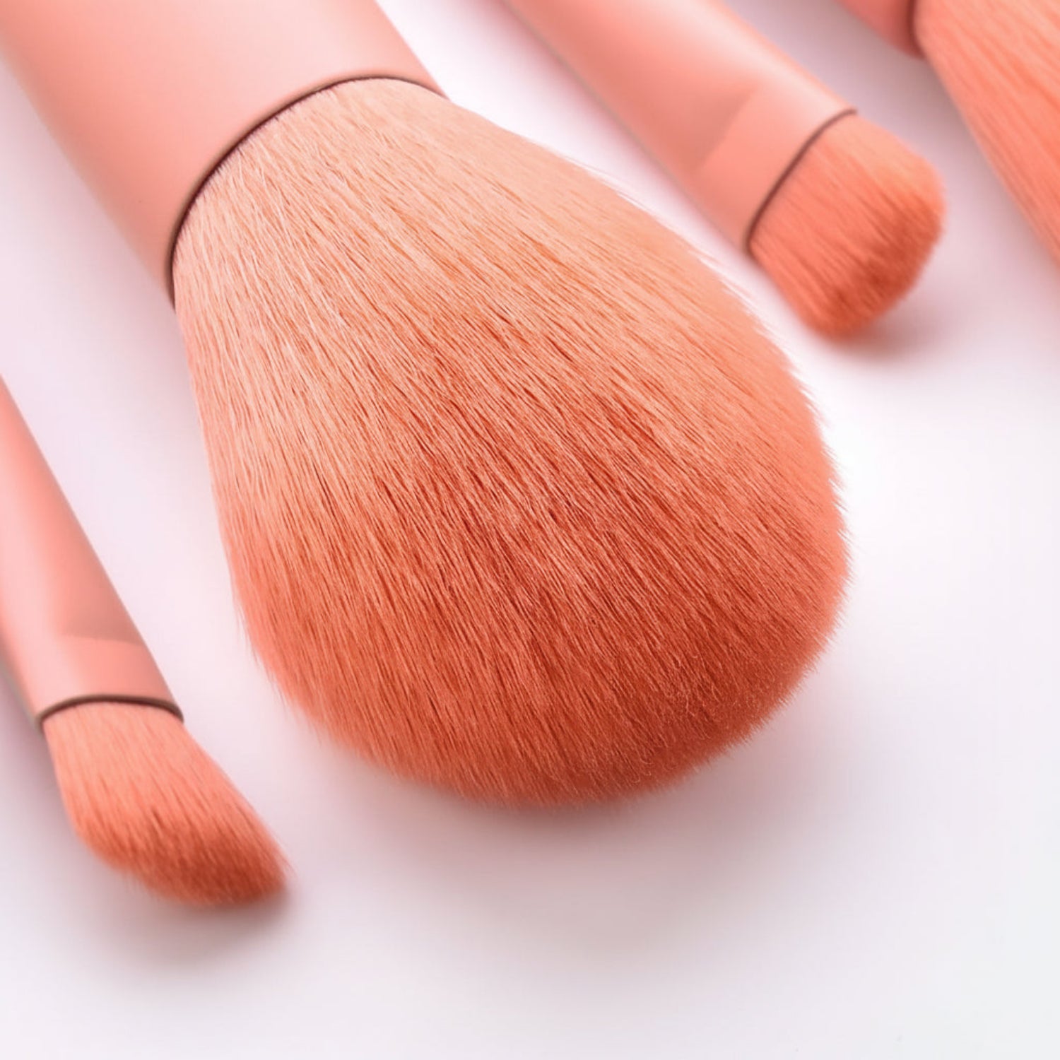 Close-up of premium makeup brushes with soft pink bristles and elegant wooden handles - professional quality