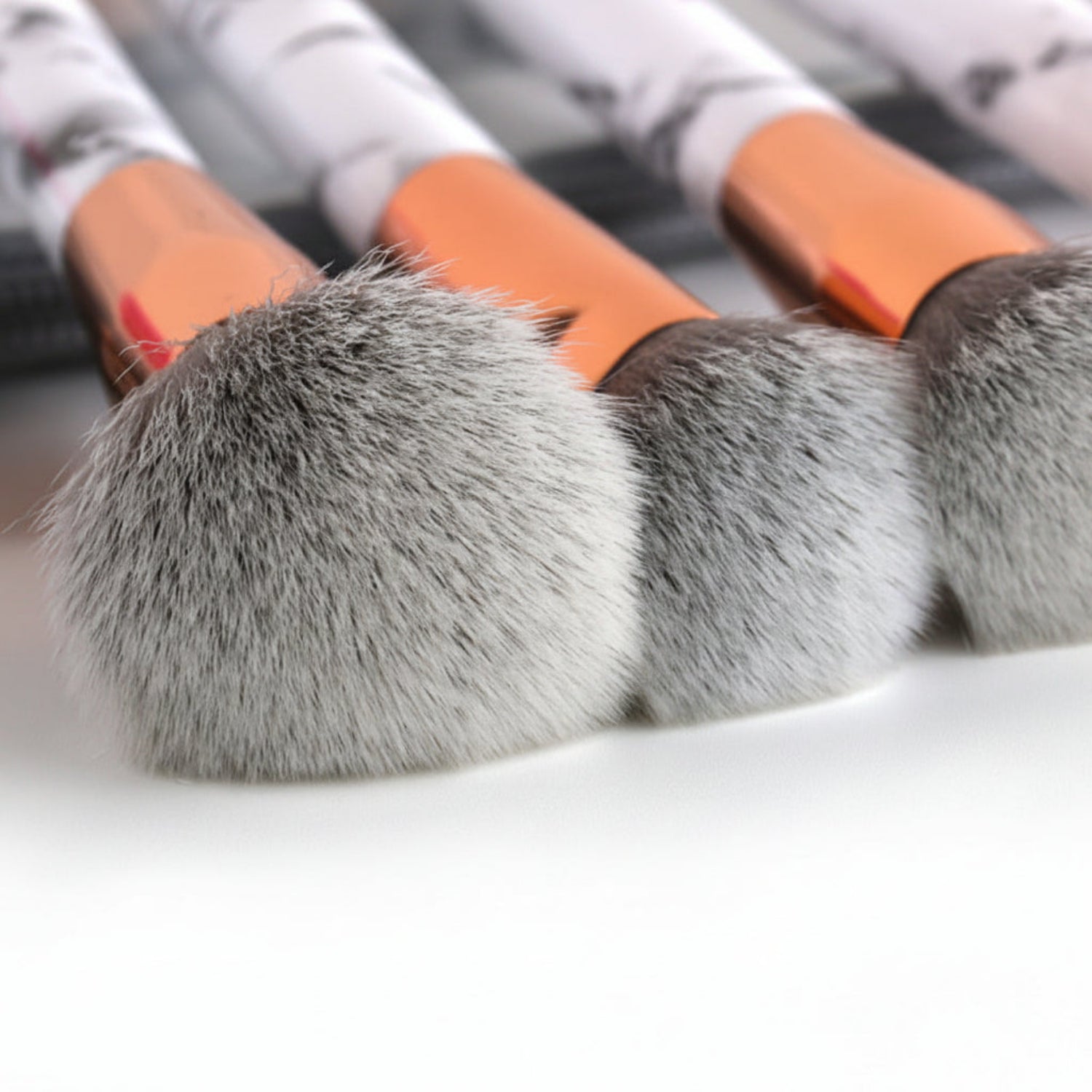 Close-up of makeup brushes with gray bristles and orange handles on a white background