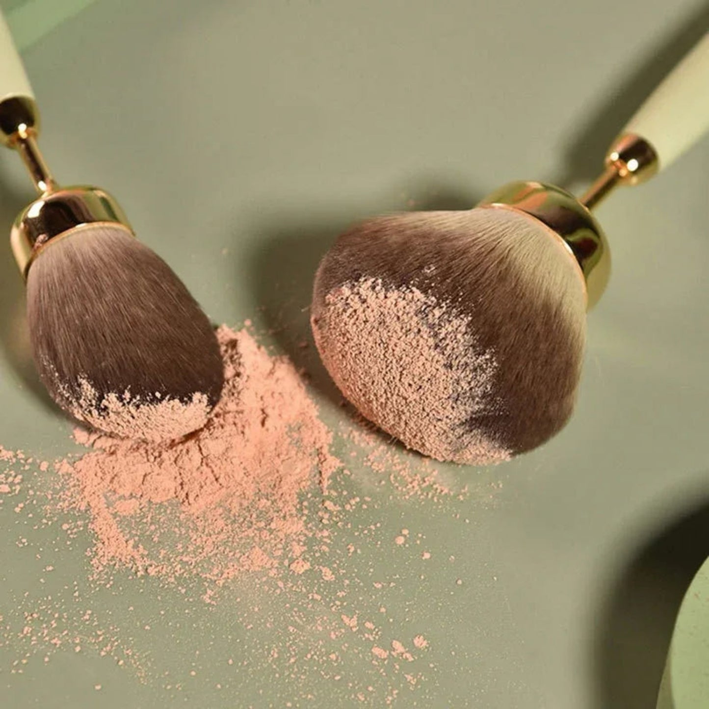 Makeup brushes with pink powder on a green background