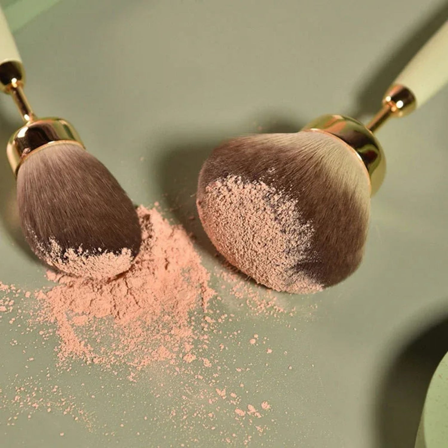 Makeup brushes with pink powder on a green background